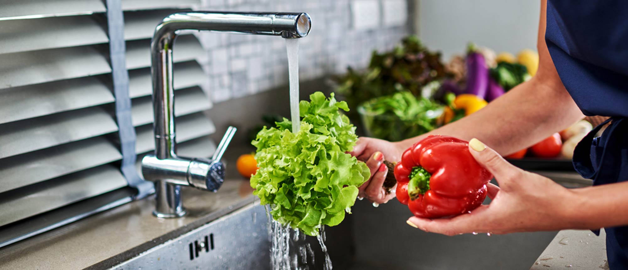 Woman washing vegetables in her kitchen sink
