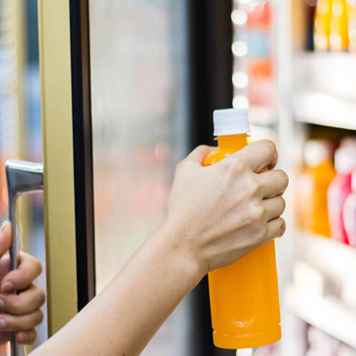 Customer taking a bottled beverage from a commercial stand-up cooler | Commercial Refrigeration